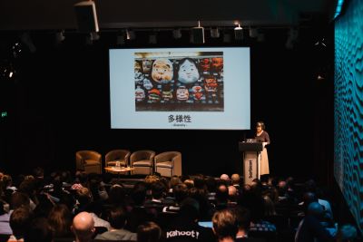 Margaret Lee is speaking (for the first time) at the Leading Design conference in 2016. She’s standing behind a lectern; a slide is projected on the screen next to her on the stage