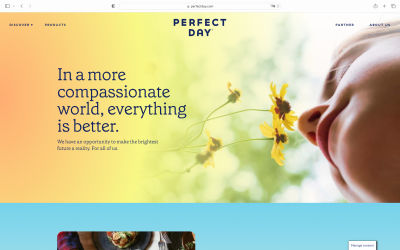 The Perfect Day hero image with a soft-colored gradient overlay effect positioned from left to right. The gradient overlay effect colors go from orange to yellow and green and blend with the hero image (a girl smelling a yellow flower). The headline says, ‘In a more compassionate world, everything is better.’ The sub-heading says, ‘We have an opportunity to make the brightest future a reality. For all of us.’